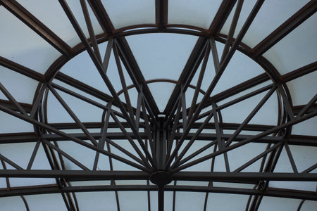 Dynamic low-angle shot of an architectural dome's intricate metal framework and glass panels, creating a compelling abstract pattern.の写真素材