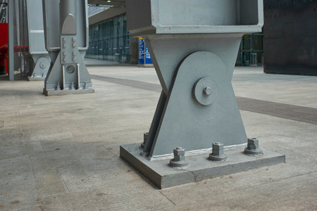 Close-up of a robust steel support beam anchored by large bolts to a concrete base, showing industrial strength and modern structural design.の写真素材