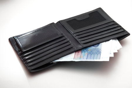 An open black leather wallet revealing a fan of 20 Euro banknotes, suitable for themes of spending, budgeting, or currency.の写真素材