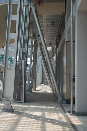 Perspective view of a contemporary building's interior or exterior walkway, defined by striking metal beams, columns, and a structured ceiling, creating a modern industrial feel.の写真素材