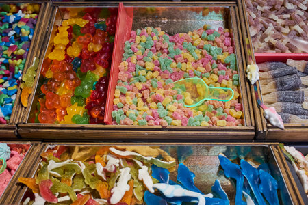 A colorful variety of gummy candies, including bears and sharks, displayed in bins at a market stall. A vibrant assortment of sweet treats and sugary snacks.の写真素材
