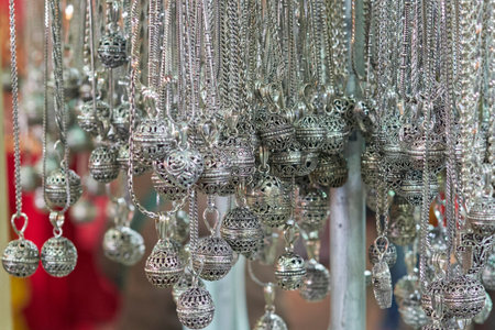Close-up of ornate silver pendants hanging in a traditional market. Intricate filigree designs, handcrafted with cultural and artistic details. Ideal for fashion or cultural themes.の写真素材
