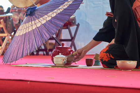 Scene of a Japanese tea ceremony with teapot, cups, a purple parasol, and Taiko drums in the...