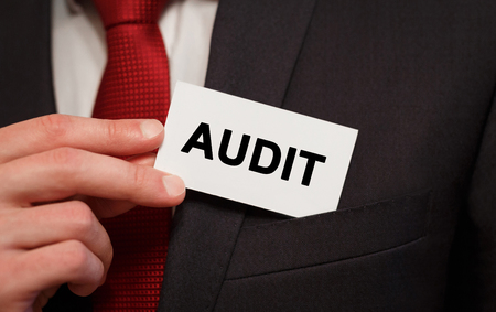 Businessman putting a card with text Audit in the pocketの写真素材