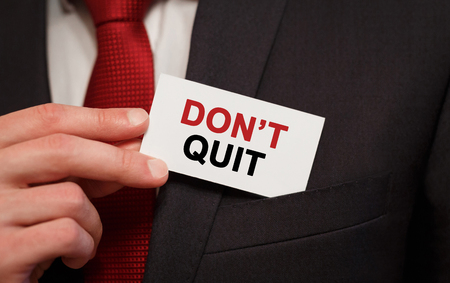 Businessman putting a card with text Dont Quit in the pocketの写真素材