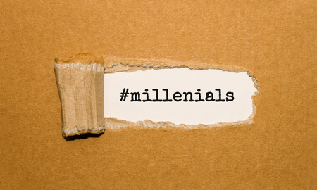 The text millenials appearing behind torn brown paperの写真素材