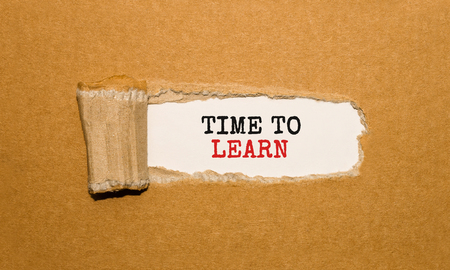 The text Time to Learn appearing behind torn brown paperの写真素材
