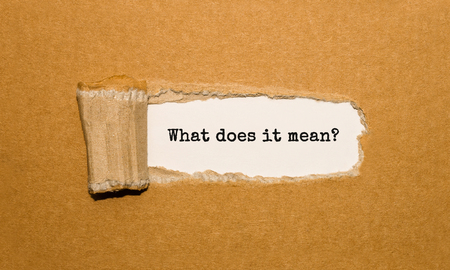 The text What does it mean appearing behind torn brown paperの写真素材