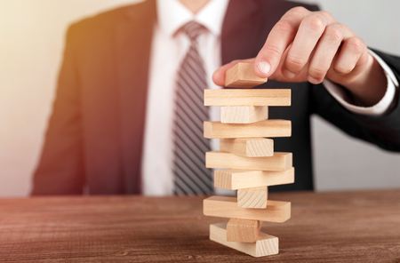 Businessman placing wooden block on a tower. Planning, risk and business strategy concepts.の写真素材
