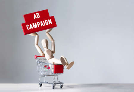 Wooden man hold a wooden block with word Ad Campaign, conceptの写真素材