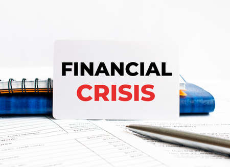 Business card with text Financial Crisis lying on blue notebook, conceptの写真素材