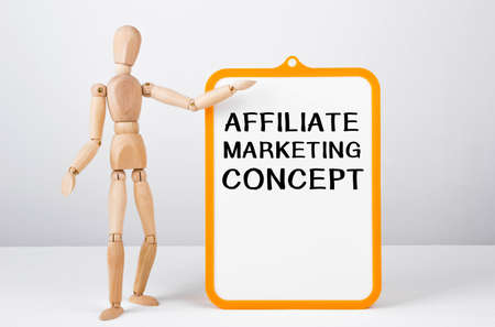Wooden man shows with a hand to white board with text Affiliate Marketing Concept.の写真素材