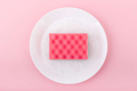 Pink sponge on the pink background. Top view. Cleaning and housewashing concept