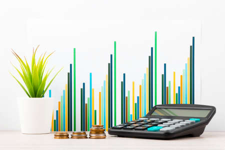 Calculator, stack of coins In front of desk with business charts and graphs. Business planning,...