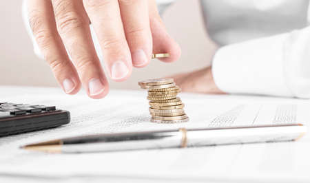 Businessman or accountant counting money and making stack of coins on financial data. Financing, Accounting and Banking Conceptの写真素材