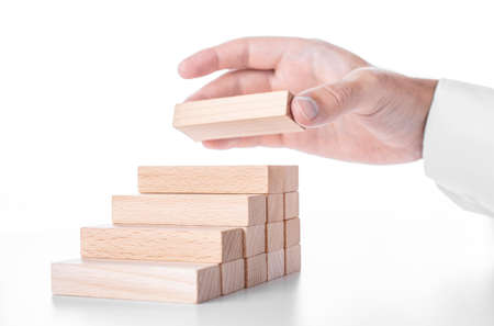 Businessman builds a ladder from wooden blocks. Concept of business growth and success.の写真素材