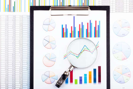 Magnifying glass lying on business charts and graphs. Business planning, accounting, analysis,...