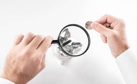 Man looking at piggy bank throught magnifying glass. Concept of Finance, crisis and saving moneyの写真素材