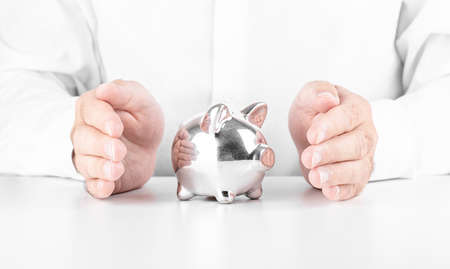 Man saving piggy bank with his hands. Concept of Finance, crisis and saving moneyの写真素材