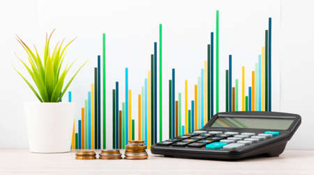 Calculator, stack of coins In front of desk with business charts and graphs. Business planning, accounting, analysis, financial planning and data Analysis conceptの写真素材