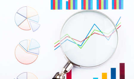 Magnifying glass lying on business charts and graphs. Business planning, accounting, analysis,...