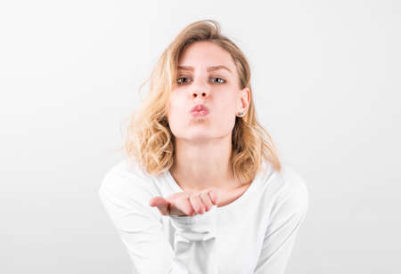Portrait of beautiful woman in white shirt sending an air kiss.の写真素材