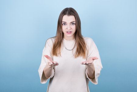Portrait of beautiful pretty attractive lovely girl showing i dont know gesture isolated on blue...