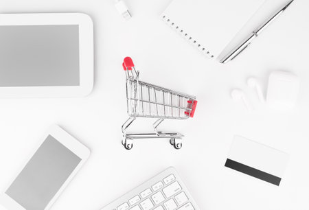 Shopping online concept. Small red trolley and gadgets on the table.の写真素材