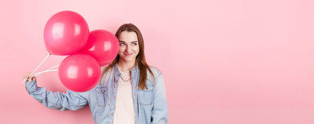 Young caucasian woman holding balloons with happy expression and celebrating a Valentine's day isolated over a pink backgroundの写真素材