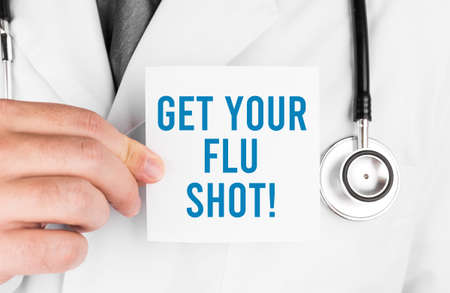 Doctor holding a card with text Get your flu shot, medical conceptの写真素材