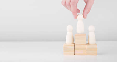 Businessman hold wooden man representing leader steps up success with standing on the pedestal. Concept of leadership and career growth.の写真素材