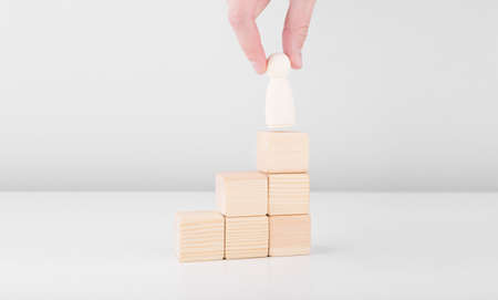 Businessman hold wooden man representing leader steps up success with standing on top of staircase. Concept of leadership and career growth. Copyspace.の写真素材