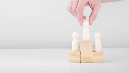 Businessman hold wooden man representing leader steps up success with standing on the pedestal. Concept of leadership and career growth.の写真素材