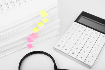 Stack of report financial data with magnifying glass and calculator. Concept of business, finance and data research.の写真素材