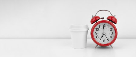 Red alarm clock with coffee cup on white wall backgroundの写真素材