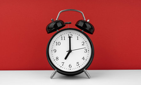 Black alarm clock on a red backgroundの写真素材