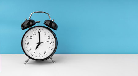 Black alarm clock on blue backgroundの写真素材