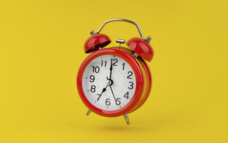 Red alarm clock hangs in the air on yellow backgroundの写真素材