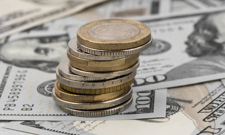 Stack of golden coins on dollar bills on a table.の写真素材