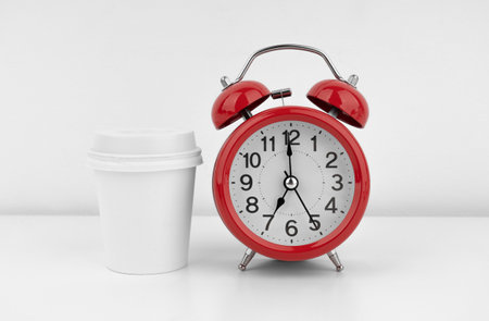 Red alarm clock with coffee cup on white wall backgroundの写真素材