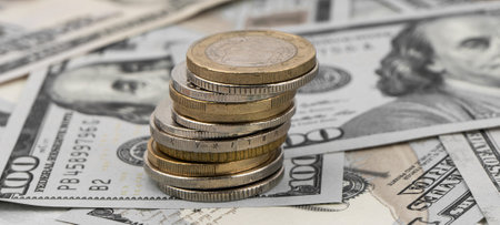 Stack of golden coins on dollar bills on a table.の写真素材