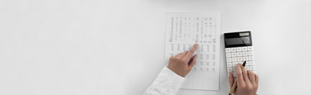 Woman using a calculator and points her finger at the numbers in the financial documents. Financial,...