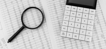 Calculator and magnifying glass on financial statement. Financial, accounting and business concept.