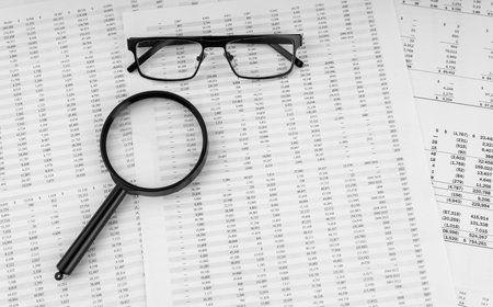 Magnifying glass and eye glasses on financial statement.の写真素材
