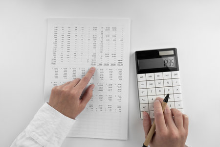 Woman using a calculator and points her finger at the numbers in the financial documents. Financial,...