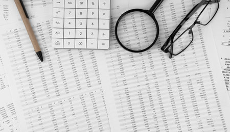 Calculator, magnifying glass, pen, eye glasses on financial statement. top view.の写真素材