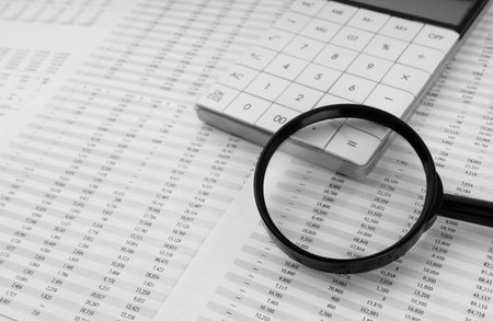 Calculator and magnifying glass on financial statement. Financial, accounting and business concept.の写真素材