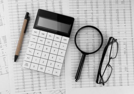Calculator, magnifying glass, pen, eye glasses on financial statement. top view.の写真素材