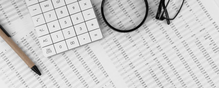 Calculator, magnifying glass, pen, eye glasses on financial statement. top view.の写真素材