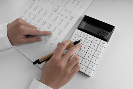 Accountant using a calculator and points her finger at the numbers in the financial statement.の写真素材